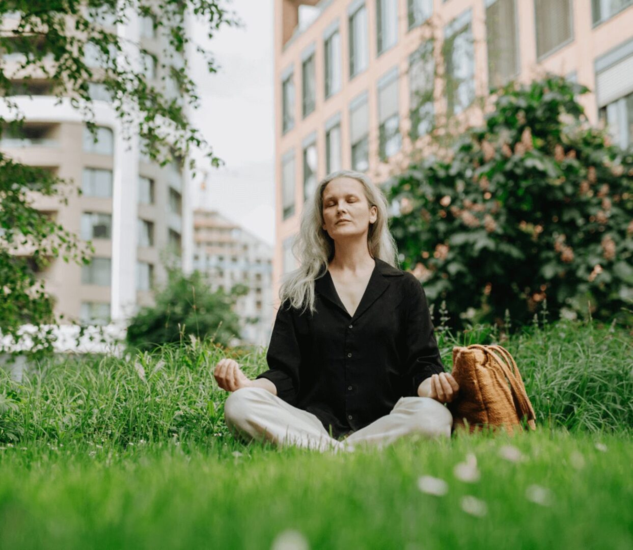 Woman meditating in city park setting.