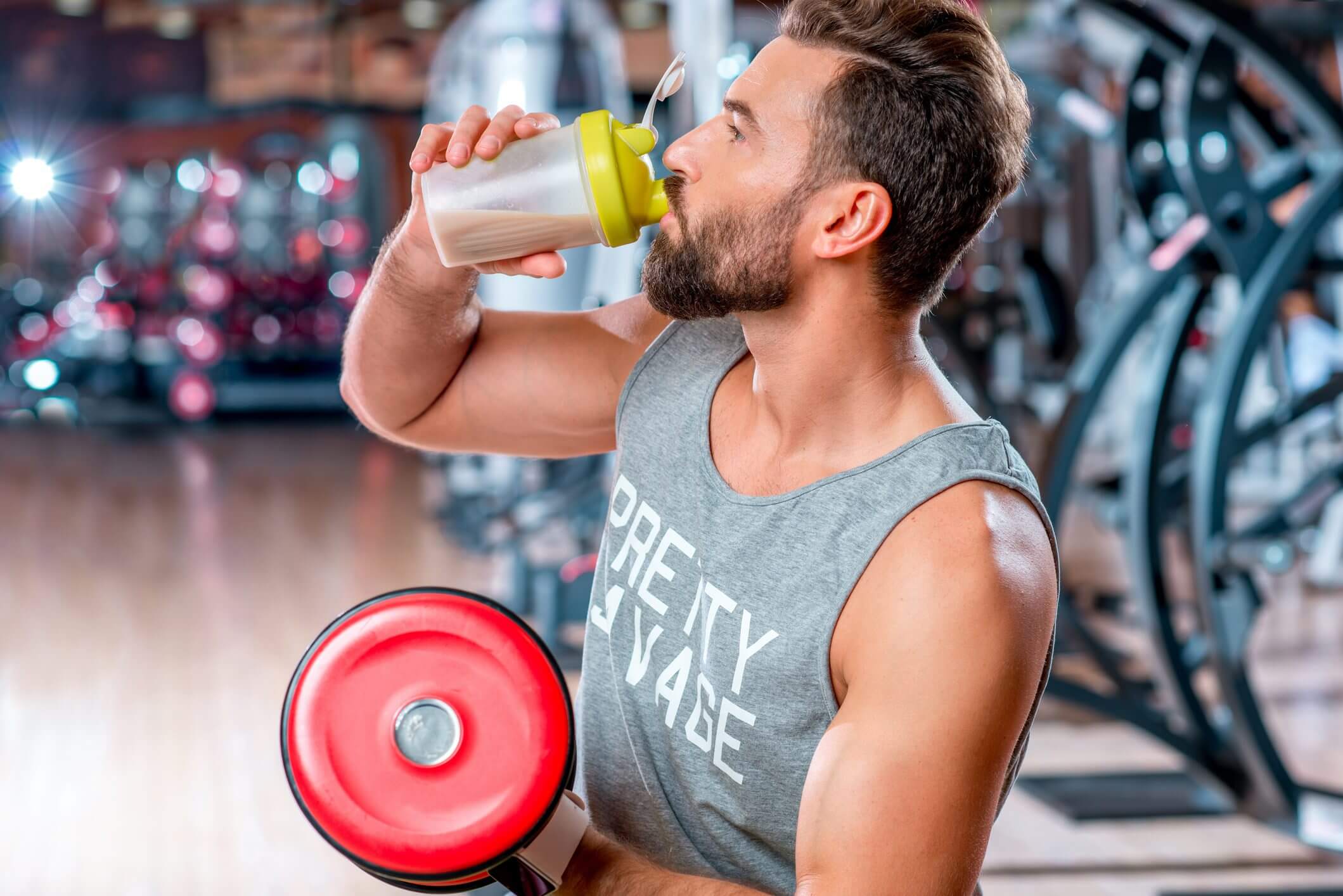 Man lifting weights while drinking water at the gym.