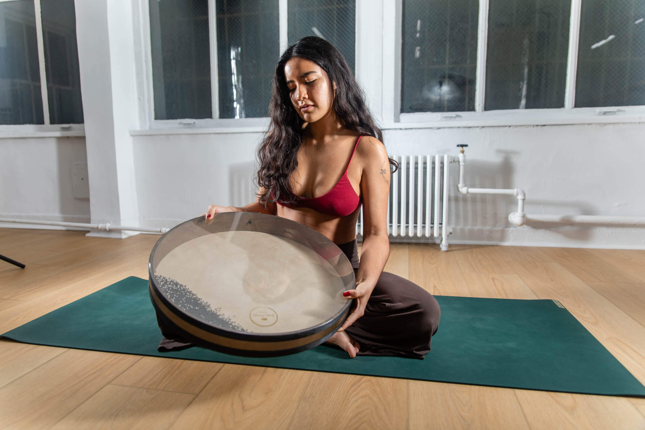 Woman holding round musical instrument on mat.
