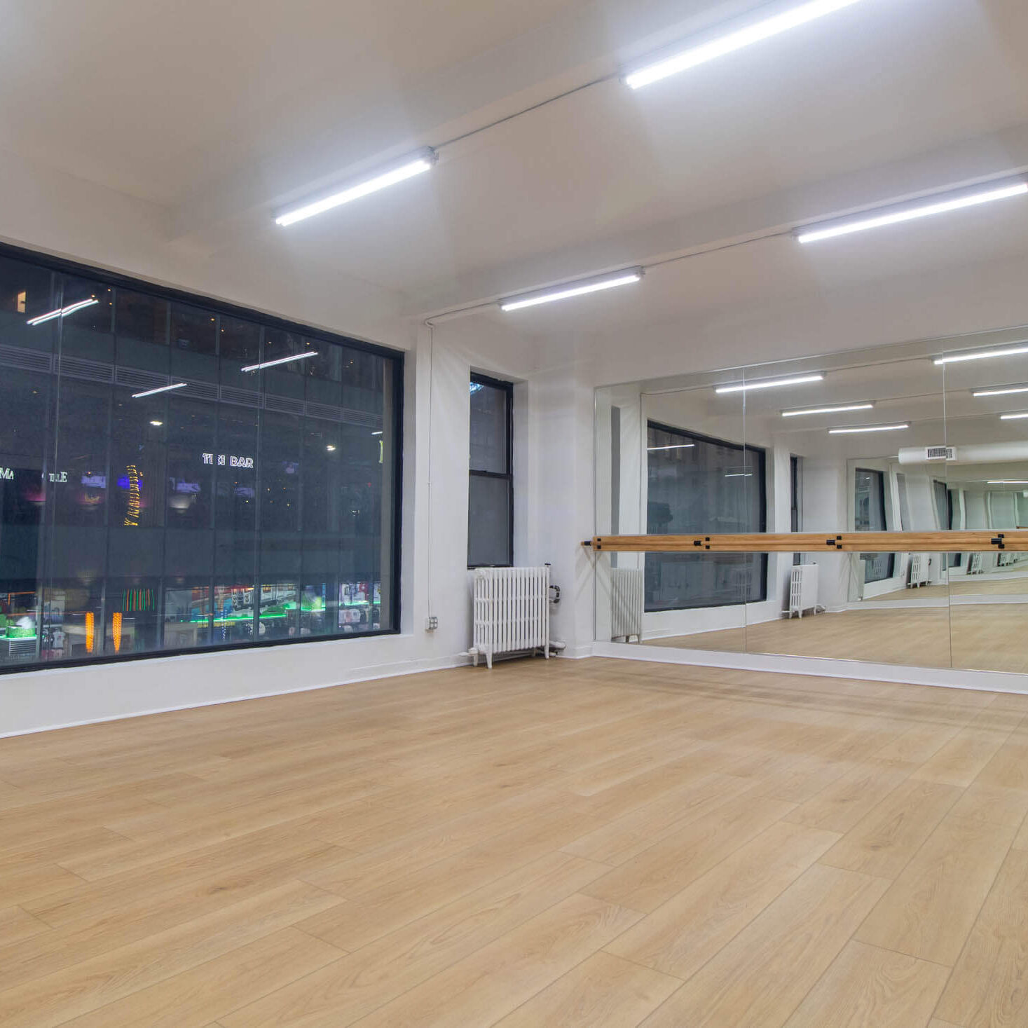 Spacious dance studio with wooden floors and mirrored wall.